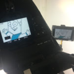 Der Bildschirm einer Kamera beim Dreh eines Erklärfilmes. Er zeigt ein fröhliches Comic Männchen mit einem blauen T-Shirt