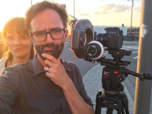 Regisseurin und Kameramann machen ein Selfie während der Magic Hour. Im Hintergrund ist eine Kamera von Canon auf einem Manfrotto Stativ zu sehen. Ein Dreh für einen Imagefilm von InZwischenZeit:Filme aus Frankfurt am Main